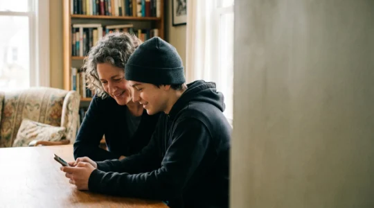 Un parent et son adolescent travaillant ensemble sur la création d'une vidéo, illustrant l'accompagnement bienveillant dans la création de contenu numérique