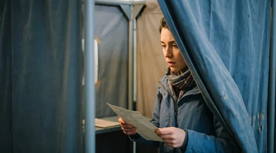 Jeune adulte dans un isoloir de vote, découvrant son bulletin de vote avec concentration et émotion, symbole du passage à la majorité électorale